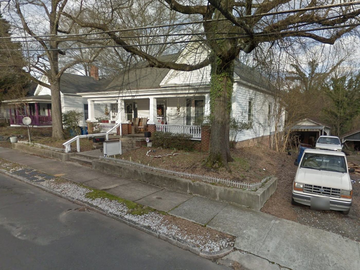 Before: the same house in white siding with a bare dirt yard and a truck in the drive.